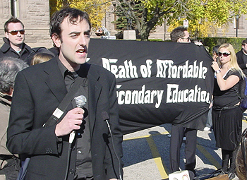 Funeral Service — Jesse Greener, Ontario chairperson of the Canadian Federation of Students, delivers a eulogy for affordable post-secondary education in Toronto Oct. 30 as mourners look on.